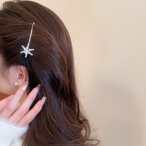 Macro shot of a snowflake-shaped hair clip with shimmering white rhinestones on hair