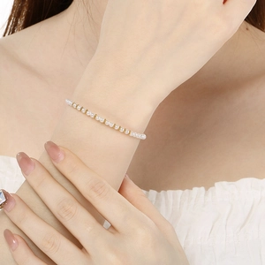Gros plan élégant d'un bracelet de perles avec des billes dorées porté au poignet chic