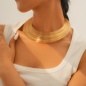 Nahaufnahme einer mehrlagigen goldenen Metallkette an einem Model im minimalistischen Stil
