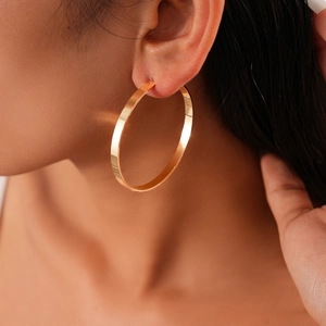 Close-up of model wearing large gold geometric hoop earrings with polished finish