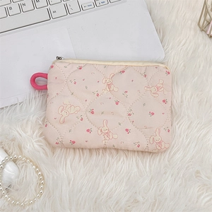 Detailed view of pink quilted cartoon bunny coin purse on a soft white plush background