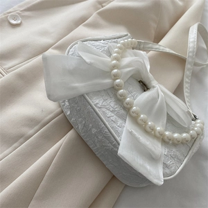 Elegant white crossbody bag with large satin bow, pearl handle, and pleated texture