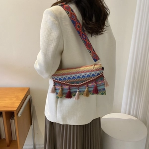 Ethnic style woven crossbody bag detail featuring colorful tassels and wide patterned strap