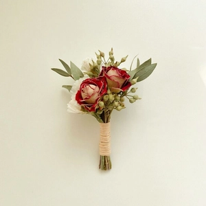 Gros plan de la boutonnière en roses séchées rouges et blanches avec eucalyptus
