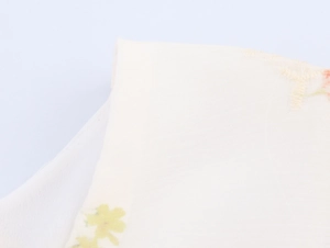 Détail de la broderie florale sur tissu crème doux avec de délicates fleurs jaunes