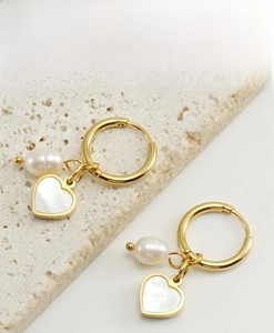 Detail of 18K gold hoop earrings with natural pearl and heart-shaped shell pendants