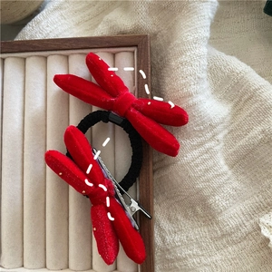 Detail of red velvet bow hair tie and clip set with gold dots on a jewelry tray