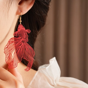 Gros plan d'une boucle d'oreille carpe koi rouge avec crochet doré sur un modèle
