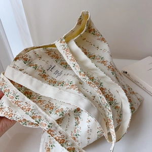 Close-up of floral canvas tote bag featuring orange patterns and a central fabric label