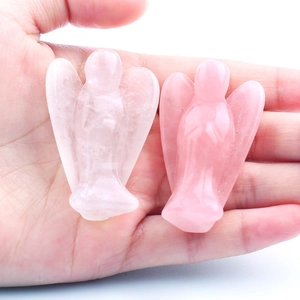 Detailed view of two rose quartz crystal angel figurines held in a hand for scale