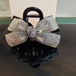Close-up of black hair claw clip featuring a sparkling rhinestone bow detail with reflection