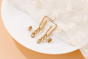 Macro shot of gold geometric chain earrings featuring rectangular hoops on white porcelain