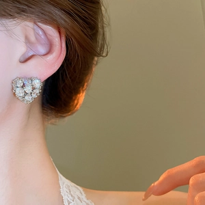 Close-up of heart-shaped zircon earrings with silver plating on a model's ear