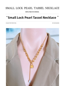Detail of titanium steel gold lock pendant with white pearl tassel on U-link chain