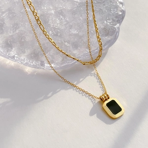 Detailed close-up of double-layer gold necklace featuring black agate geometric pendant