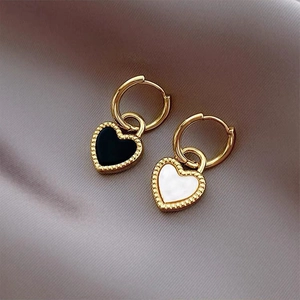 Detailed close-up of retro gold heart earrings with milgrain edges on gray silk fabric
