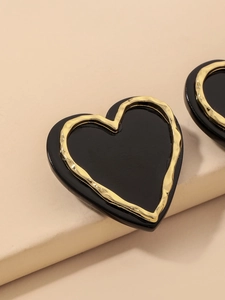 Detail of vintage heart earrings with black acrylic center and hammered gold trim
