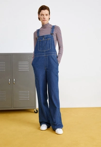 Detailed view of women's vintage loose denim overalls with colorful striped sweater
