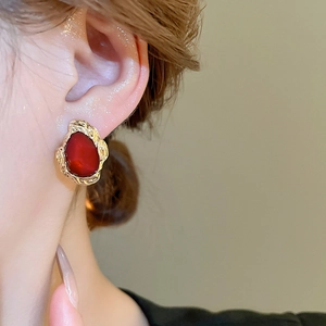 Close-up of vintage geometric earring with red teardrop stone and gold textured metal