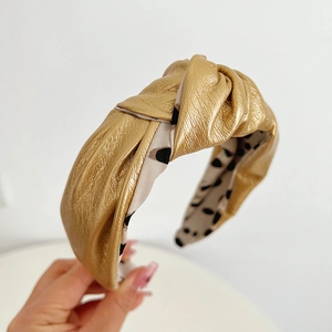 Close-up of golden leather knotted headband with polka dot lining and textured finish