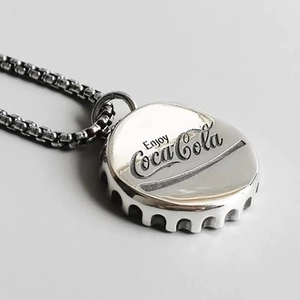 Detailaufnahme des polierten Silber-Kronkorken-Anhängers mit Enjoy Coca-Cola Gravur