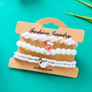 Primo piano del set di tre braccialetti natalizi con perline e ciondoli a forma di guanto