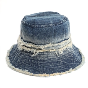 Detail shot of distressed fringe edges and frayed texture on blue denim bucket hat
