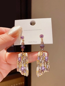 Detail of S925 silver post earrings with multifaceted purple crystal pendants and gold plating