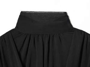Vista macro detallada del cuello alto negro con textura de gasa plisada y elegante