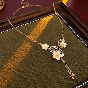 Close-up of gold flower necklace with hollow oval pendant on green fabric background