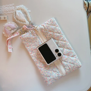 Détail de la pochette fleurie matelassée avec sangle en perles et ruban en dentelle