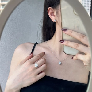 Detailed view of silver jewelry set with necklace, ring and halo studs on a model