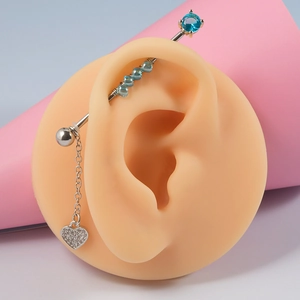 Détail d'une boucle d'oreille en argent avec perles bleues et pendentif cœur en cristal