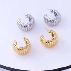 Close-up of gold and silver liquid lava style croissant earrings with vertical ribbed texture