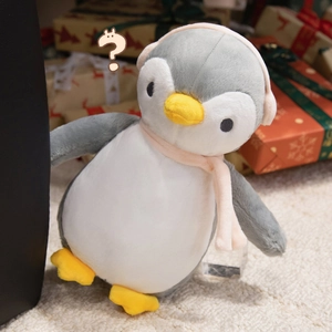 Close-up of plush penguin toy wearing a pink scarf and earmuffs in a festive gift setting