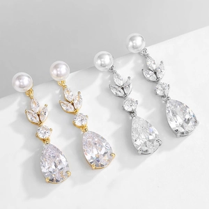 Detailed close-up of gold and silver leaf-shaped earrings with pearls and pear-cut zircons
