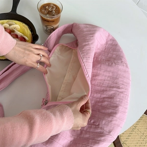 Macro view of pink quilted crescent bag with soft pleated nylon texture and zipper detail