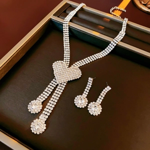 Close-up of silver heart necklace with three-row rhinestones and long tassel earrings