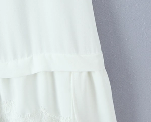 Détail de robe blanche avec bordure en dentelle brodée et texture en mousseline
