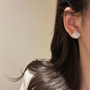 Detail shot of silver clover earrings with cubic zirconia on a female model