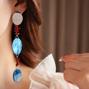 Macro view of long fringe earrings with red beads and blue marble pattern drop pendants