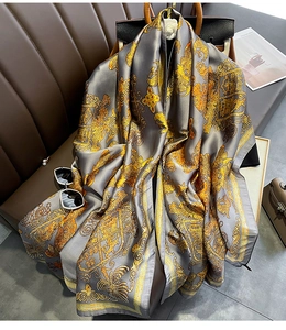 Detail of silk-like grey scarf with vintage gold Baroque patterns draped over a sofa