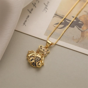 Detail of a gold bear pendant necklace with black and white crystals on a box chain