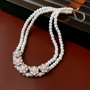 Detail of double-layer necklace with white pearl flowers and silver rhinestones