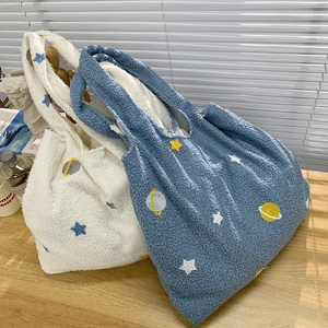 Detail of white and blue plush tote bags with cartoon star and planet embroidery