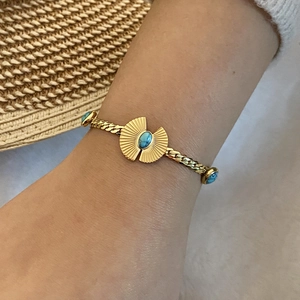 Nahaufnahme des goldenen Kordelarmbands mit Türkisstein in radialer Sternenfassung