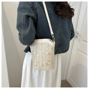 Vue latérale du sac seau en paille avec broderie florale et bandoulière en cuir PU sur modèle