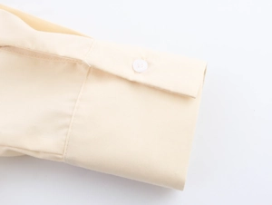 Detailansicht der gelben Hemdmanschette mit weißem Knopf und präziser Nahtführung