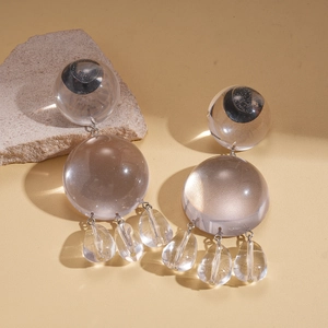 Détail de boucles d'oreilles en résine transparente avec clous argentés et gouttes
