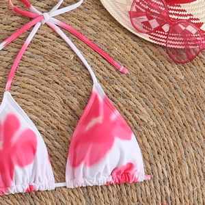 Detailed close-up of a floral bikini top with pink flowers on a straw mat background
